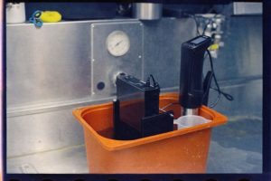 Utrustning för mätning i en orange hink på en metallbänk.